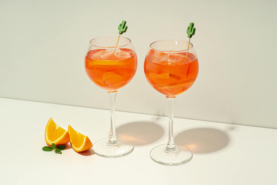 Duas taças com líquido laranja e rodelas de laranja.