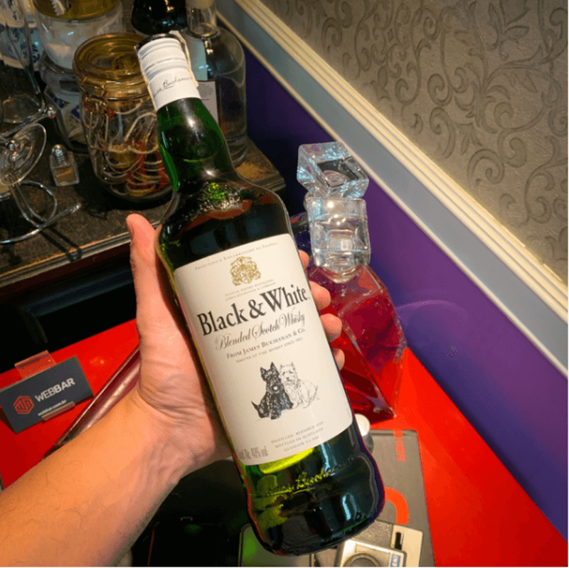 Garrafa de whisky de coloração verde e rótulo branco sendo apresentada à câmera