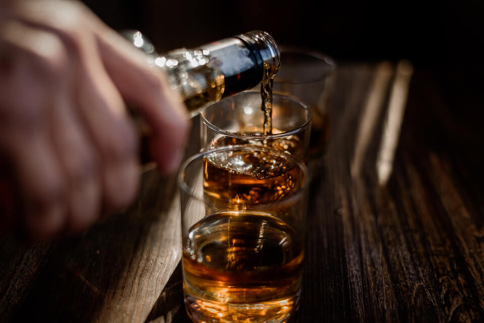 Whisky sendo servido em 2 copos.