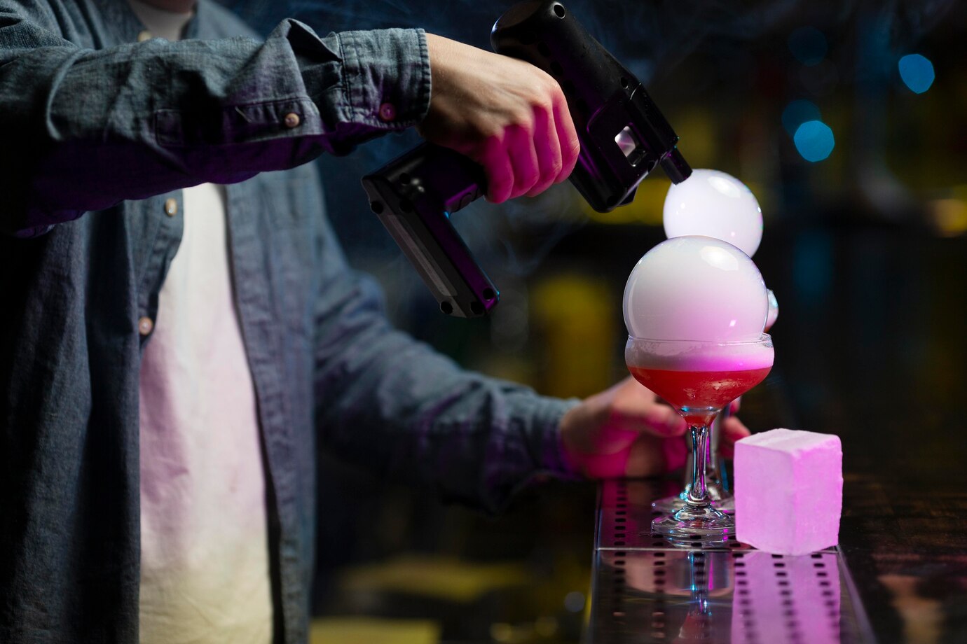 Imagem onde o bartender está decorando um drink com uma pistola de fumaça 