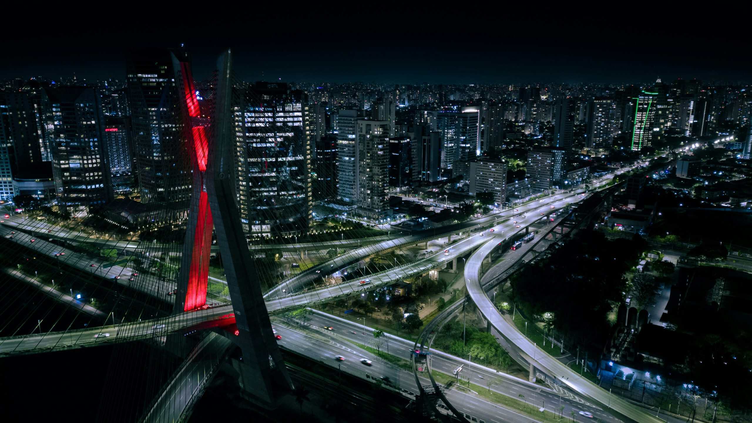 Vista da ponte na cidade de São Paulo a noite, junto de prédios.